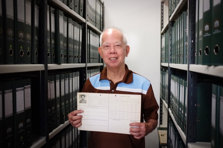 Mr Siu holding his Student Life Card. The green files contain Student Life Cards he had filed and indexed for the RAM